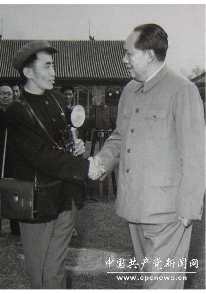 1958年，吕厚民手拿闪光灯、相机、挎包和毛主席握手。