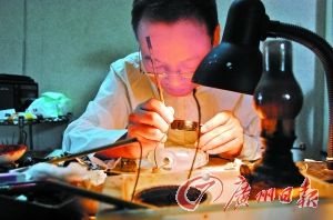 赖乙宁坐在那张简陋的桌子前，在台灯下面，手持放大镜，将那个看似简单的铁丝钩笔蘸上墨汁、颜料，探入瓶内转动提拉、写字作画。