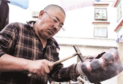 图为非遗传承人晋美正在细心制作藏民族传统金属手工艺品。 记者 高加库 摄