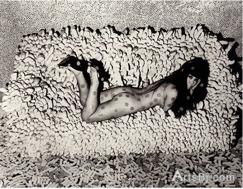 艺术家草间弥生躺在其作品《积累 No.2》（Accumulation No.2），背后是其作品《无尽之网》（Infinity Net），地板上是其作品《通心粉地毯》（Macaroni Carpet），照片尺寸不详，1966，摄影师：Hal Reiff