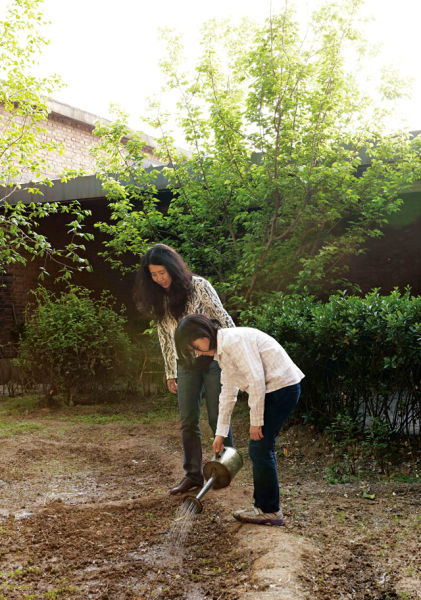 尹秀珍在工作室的菜园里种菜，女儿也帮忙浇水、除草、施肥(摄影：黄辉)