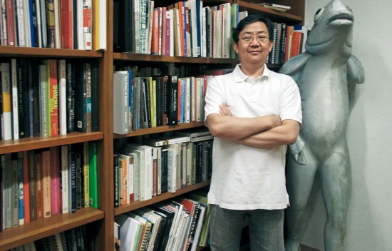 书架上的书主要分为现当代艺术、文化政策、文化管理、中国文化等，还有一格专放东南亚艺术。他旁边的雕塑是香港本地传说中的动物“卢亭”。