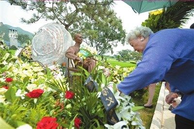 遗孀滕芳女士在墓前献上鲜花。