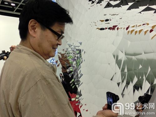 台湾资深艺术顾问陆洁民在香港巴塞尔艺博会现场兴致勃勃地拍作品
