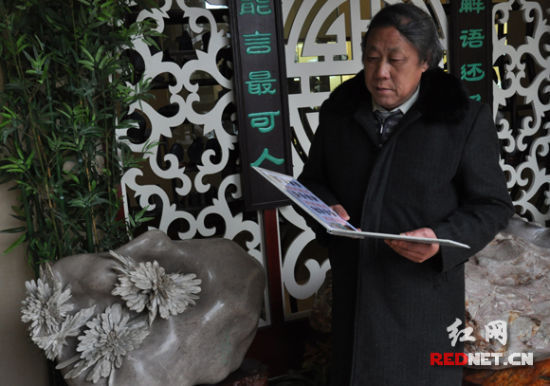 湖南省工艺美术大师曹明珠正在国家非物质文化遗产菊花石雕传承发展基地观看邮册样本。