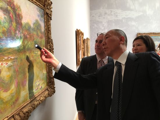 大连万达收藏机构负责人郭庆祥在仔细观看莫奈《睡莲池与玫瑰》