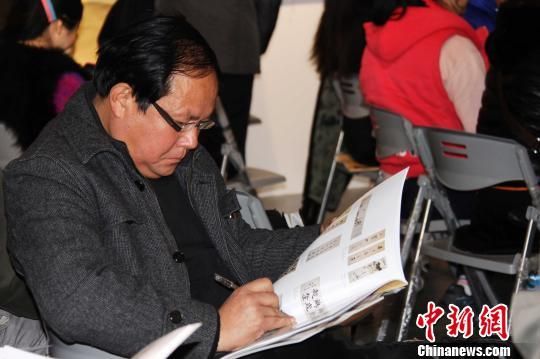 由山东省资源总公司主办的首届“慧眼识宝”书画拍卖会11月30日在济南阳光100文化艺术馆举行，图为竞拍者阅读拍卖产品图录，挑选心仪的作品。 黄品璇 摄