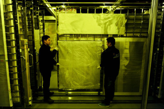 上海自贸试验区艺术品保税仓库中，工作人员正在搬运画作。