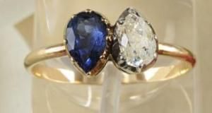 这枚直径18毫米的纯金戒指上镶嵌一颗钻石和一颗梨形蓝宝石。
