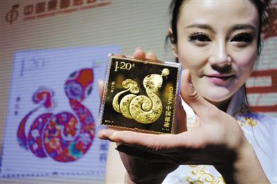 工作人员展示蛇年邮票金砖。