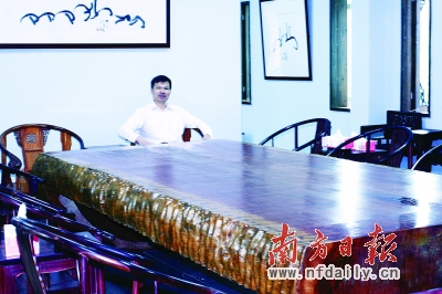 李艺和他收藏的价值上百万元的黄花梨会议桌。