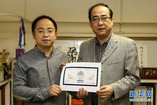 亚太经合组织第二十二次领导人非正式会议纪念邮票的设计者何洁(右)、周岳手持票样合影(摄于11月4日)。 新华社记者 张玉薇摄