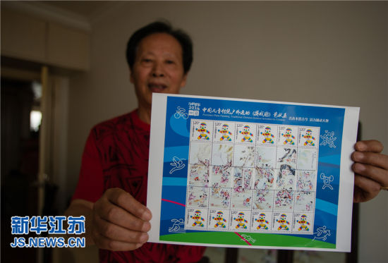 6月24日，黄乃海在家中展示根据《婴戏图》设计的个性化邮票样票。(新华社记者 李响摄)