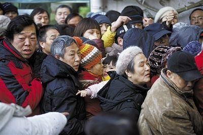 一市民抱着小孩排队买马年邮票。昨日，2014马年生肖特种邮票开卖，北京南区邮票公司门前排起了两三百米的购票长队。本版图片（除署名外）/新京报记者 周岗峰 摄