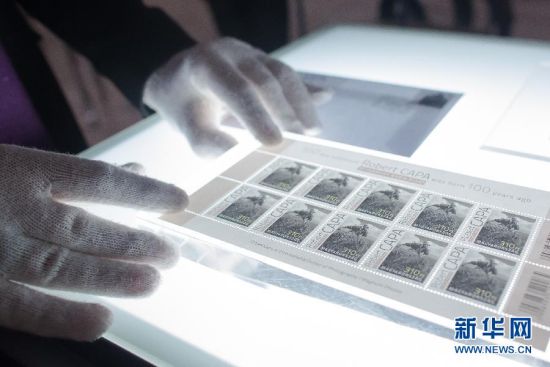 10月16日，在匈牙利布达佩斯民族博物馆举行的罗伯特·卡帕摄影展上，一名工作人员摆放卡帕纪念邮票。