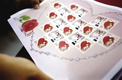 邮政营业员展示市民定制的夫妻结婚照个性化邮票