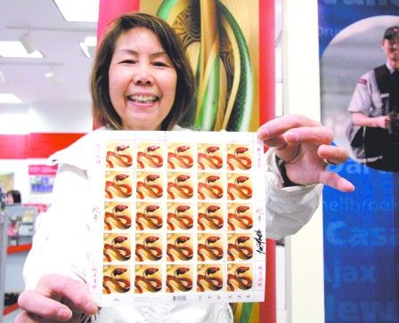 大清早前往邮局排队的刘月娴开心地向记者展示带有设计师签名的蛇年国内邮票。(加拿大《明报》)